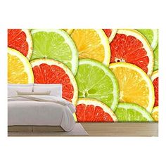 a bed sitting next to a wall covered in oranges and limes on top of it