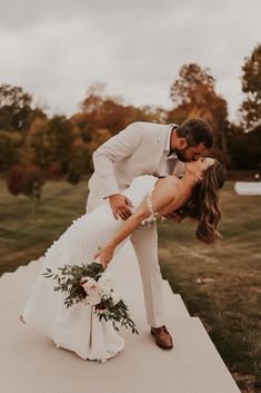 a bride and groom kissing on the edge of a walkway