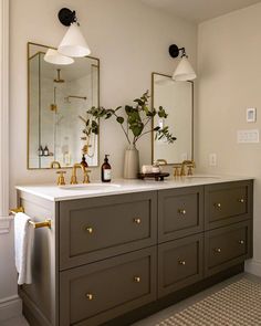 a bathroom with two sinks, mirrors and plants in vases on the counter top