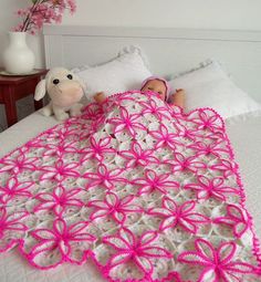 a crocheted baby blanket is laying on a bed next to a stuffed animal