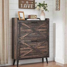 a wooden cabinet with two doors and some pictures on the wall next to a door