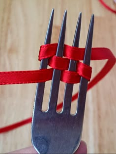 a fork wrapped in red ribbon sitting on top of a wooden table