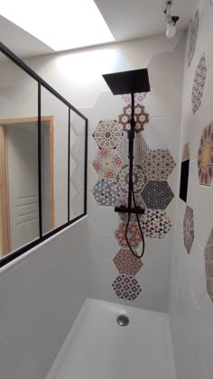 a bathroom with white walls and colorful tiles on the shower wall, along with a black faucet