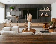 a living room filled with furniture and a flat screen tv mounted on the wall above it