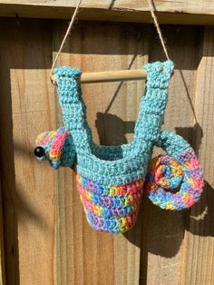 a crocheted bag hanging on a wooden fence with a hook in the shape of a slotter