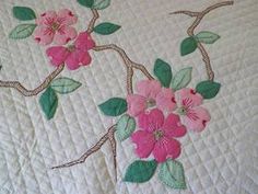 a quilt with pink flowers and green leaves on it