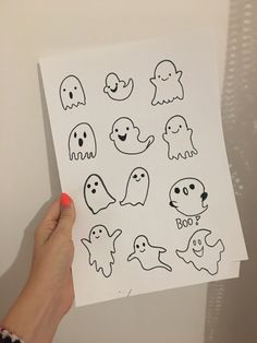 someone holding up a piece of paper with ghost stickers on it