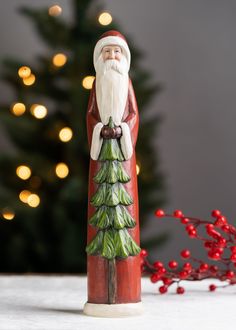 a santa clause figurine standing next to a christmas tree