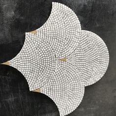 three white and gold mosaic tiles on a black background, with one circle shaped like an umbrella