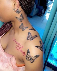 a woman with butterflies on her back shoulder and chest tattooing it's name