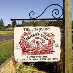 a sign that is on the side of a building near grass and trees, with a road in the background