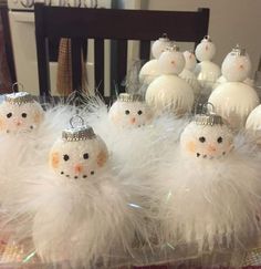 snowman ornaments are sitting on a table with white feathers and other decorations in the background