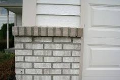 a fire hydrant sitting on the side of a brick wall in front of a house