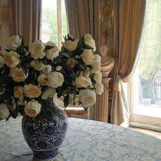 a vase filled with white flowers sitting on top of a blue and white table cloth