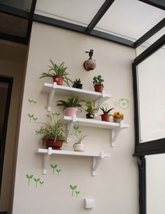 the wall is decorated with plants and potted plants on white shelve shelves