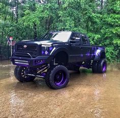 a black truck with purple wheels parked in the mud