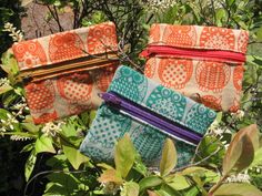 three purses sitting on top of a lush green tree filled with leaves and flowers