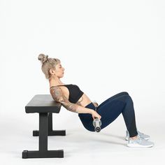 a woman sitting on top of a bench with a dumbbell in front of her