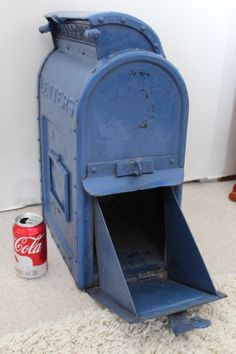 an old blue mailbox sitting on the floor next to a can