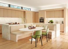 a kitchen with wooden floors and white table surrounded by green chairs next to a bench