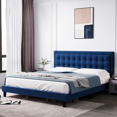 a bed with blue headboard and white sheets in a room next to a window