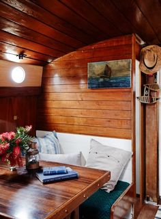 a wooden table with books and flowers on it in front of a wall that has wood paneling