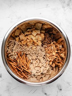 a metal bowl filled with lots of different types of crackers in it on top of a marble surface