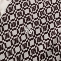 a black and white checkered shirt with a pin on it