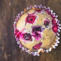 a muffin with blueberries and raspberries in it sitting on top of a wooden table