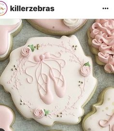 decorated cookies with pink and white icing are arranged on a blue tablecloth in the shape of ballerinas