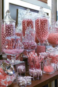 a table topped with lots of candy covered in pink and white candies next to a mirror