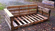 a wooden bench made out of pallets sitting on the ground next to a tree