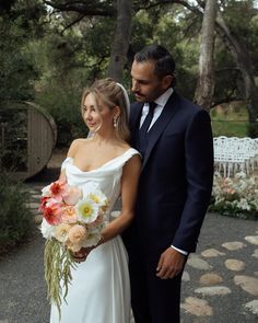 the bride and groom are standing together outside