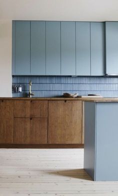 an empty kitchen with blue cabinets and wood flooring on the walls, along with a counter top