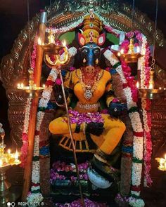 an idol is sitting in the middle of a stage with candles and flowers around it