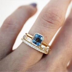 a woman's hand with two gold rings and an aqua blue ring on it