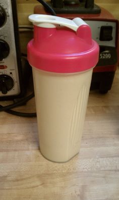 a pink and white blender sitting on top of a wooden table next to a toaster oven