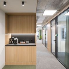 an office hallway with wooden cabinets and black counter tops, along with sliding glass doors