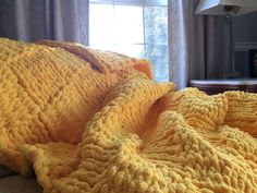 a yellow blanket is laying on a bed