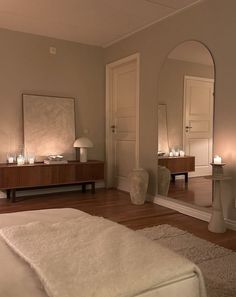 a bedroom with a bed, mirror and candles on the floor in front of it