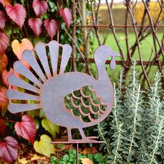 a metal turkey standing in front of some plants