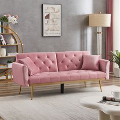 a pink couch sitting in a living room next to a white rug and table with vases on it