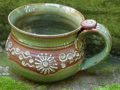 a green and brown coffee mug sitting on the ground