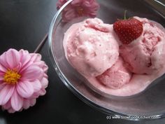 two scoops of ice cream in a glass bowl with pink flowers on the side