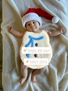 a baby laying on top of a bed wearing a santa hat and holding a cookie