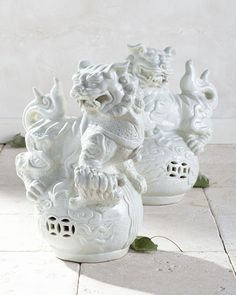 three white ceramic figurines sitting next to each other on a tile floor in front of a wall