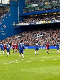 the soccer players are standing on the field in front of an audience at a stadium