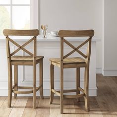 two wooden chairs sitting next to each other in front of a window