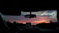 the sun is setting in the distance as seen from inside a car