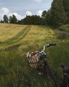 a bicycle parked in the grass with a basket on it's handlebars